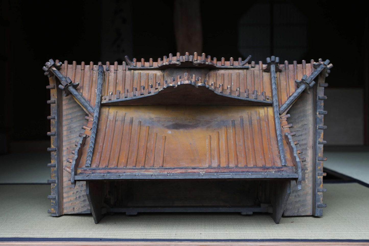An old, wooden musical instrument with a curved backrest and a wooden frame, sitting on a wooden platform.