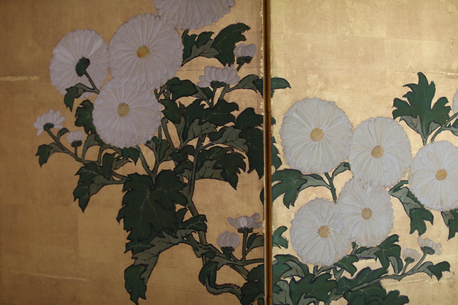 a close-up view of a painting or artwork depicting white flowers with green leaves.