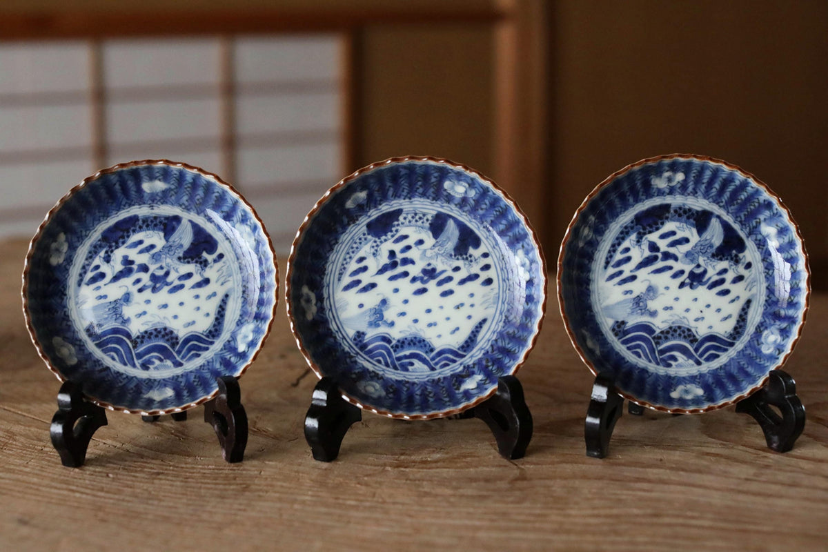 Three blue and white plates with intricate designs are displayed on a wooden surface.