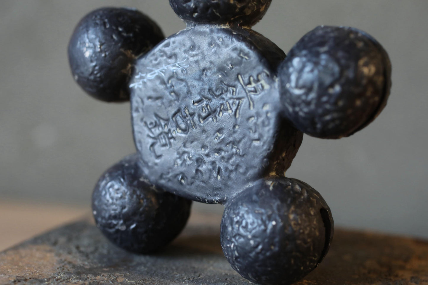 A close-up image of a black, textured metal object resembling a bear or a similar animal figure.