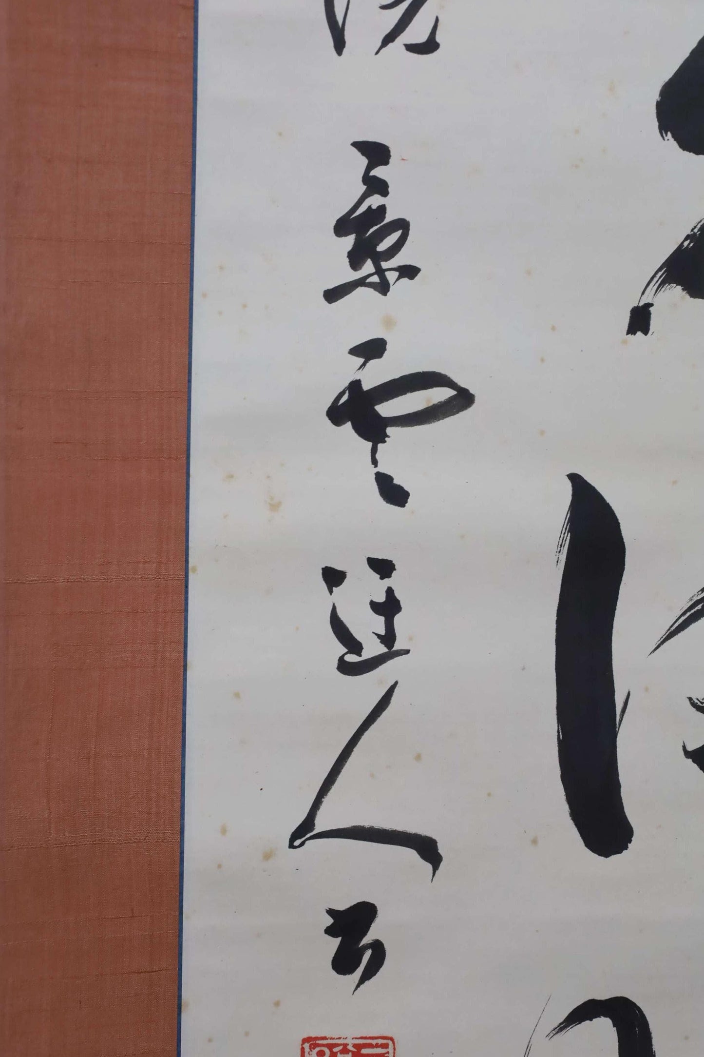 a close-up view of a piece of Asian calligraphy on a white background. The calligraphy consists of various characters and brushstrokes, creating a visually striking and intricate design.