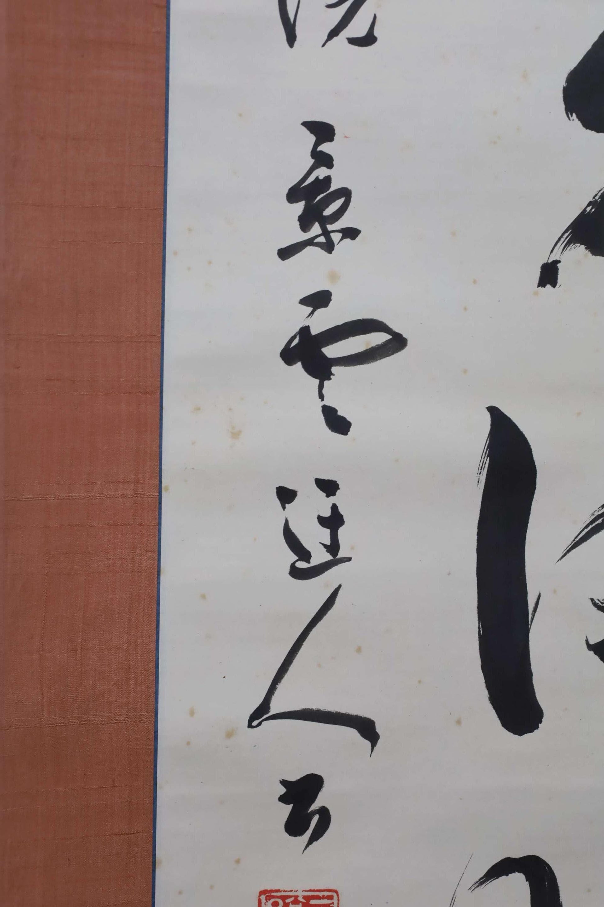 a close-up view of a piece of Asian calligraphy on a white background. The calligraphy consists of various characters and brushstrokes, creating a visually striking and intricate design.