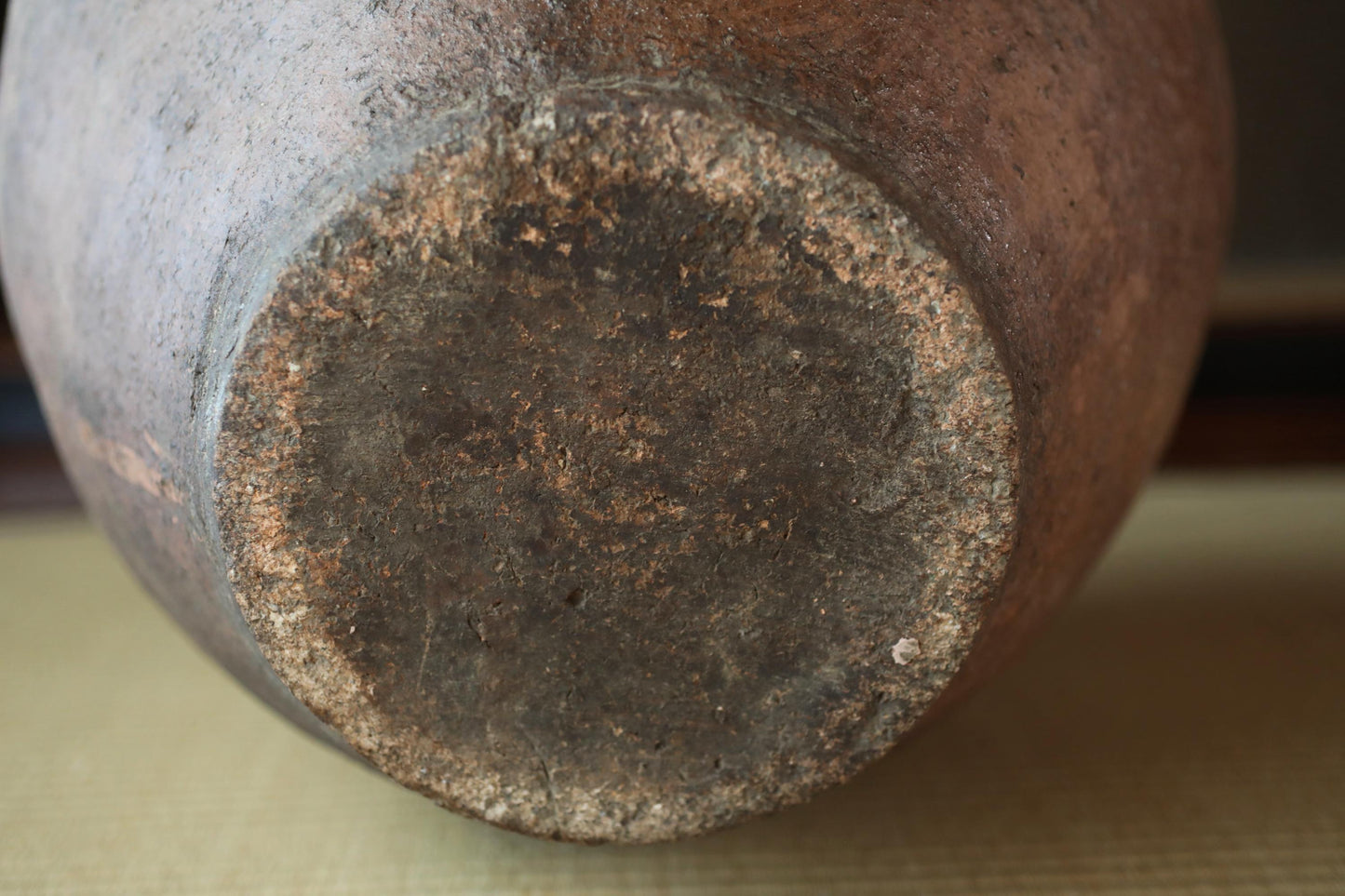 the bottom part of a large, brown, and weathered vase or pottery piece.