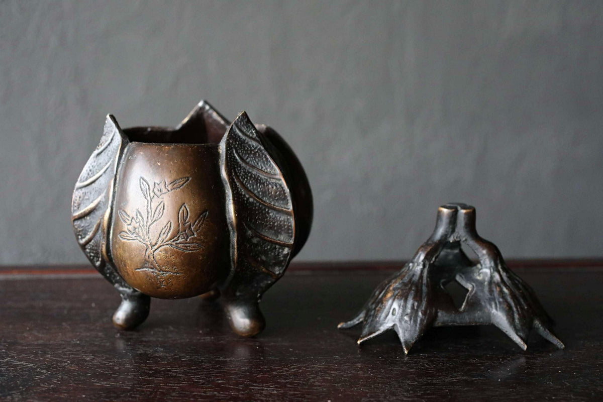 a decorative bronze vase with a tree design on it, placed on a dark surface.