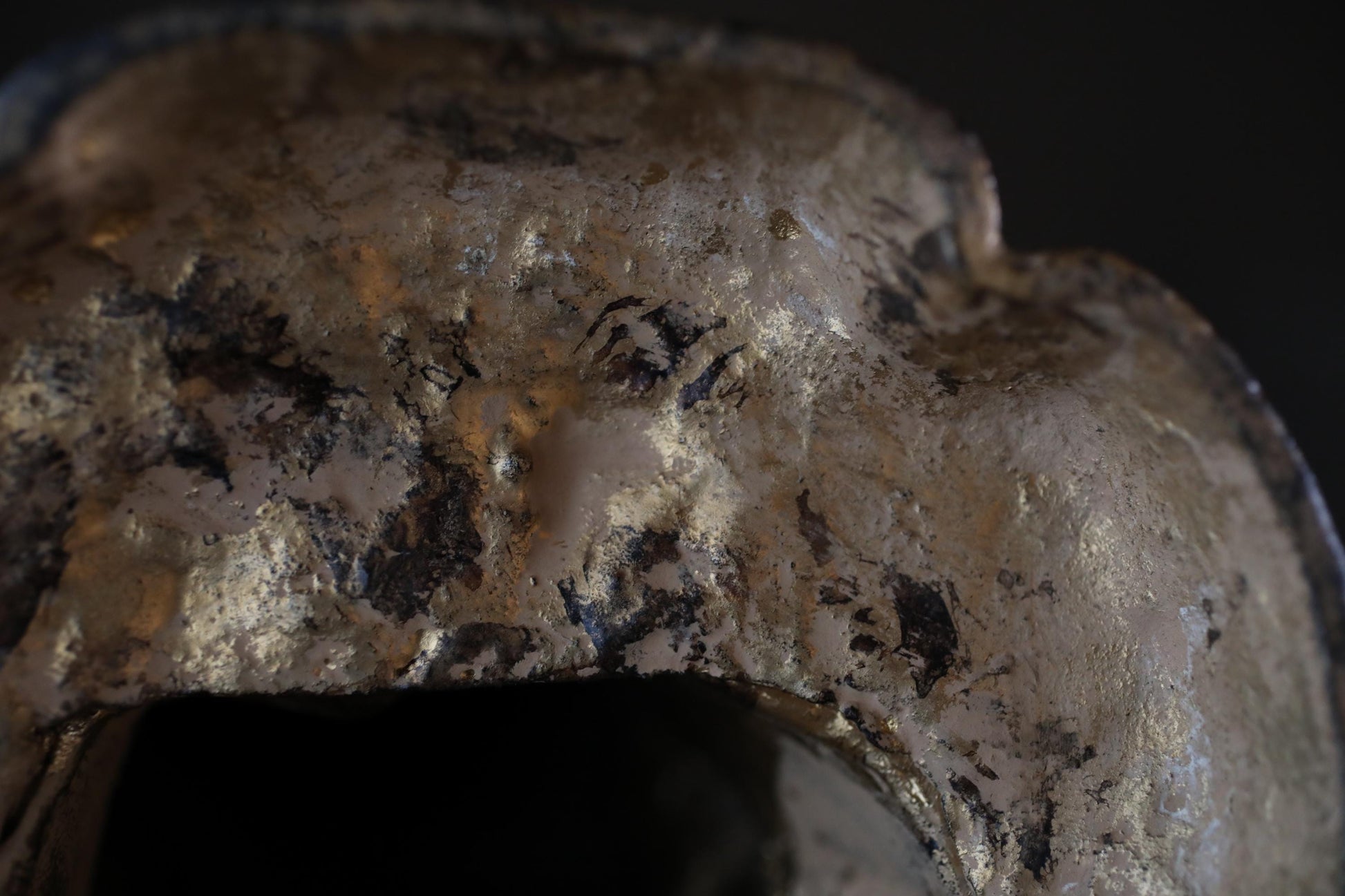a close-up view of a weathered, textured surface with a mix of gold and black colors.