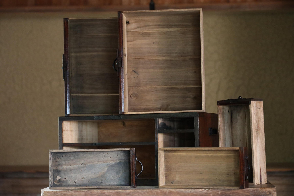 A collection of wooden boxes and trays stacked on top of each other, with some of the boxes open, revealing their interiors.