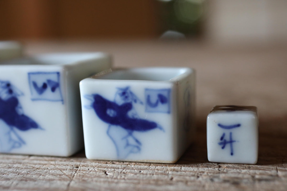 three small ceramic cups with blue designs on them, placed on a wooden surface.