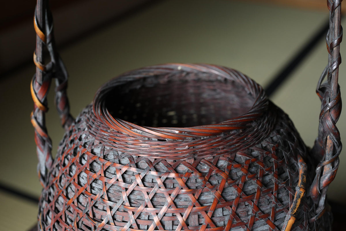 A close-up view of a woven basket with a dark brown color and intricate patterns, featuring a central opening.