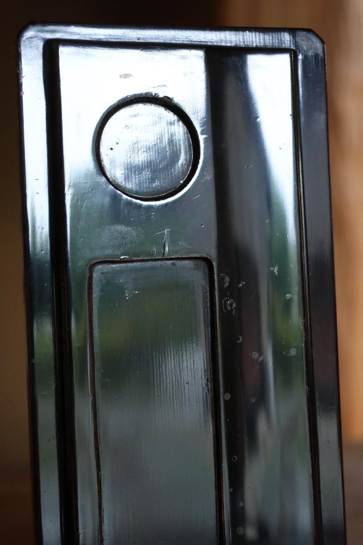 a close-up view of a metallic surface, possibly a door handle or a metallic panel, with a circular cutout in the center.