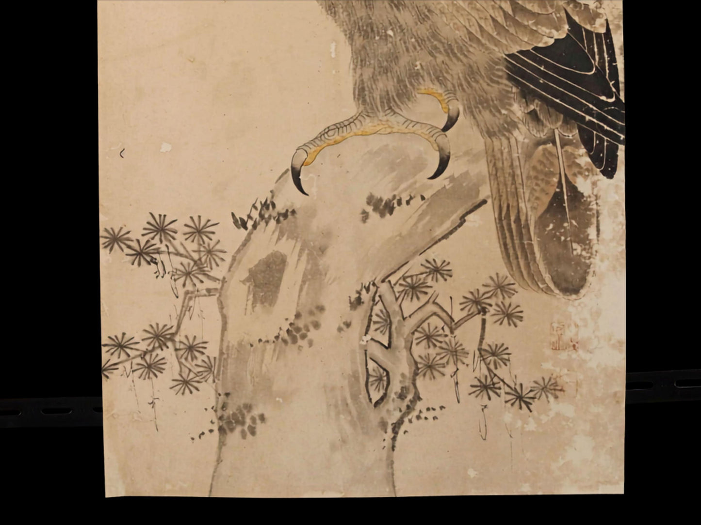 The image is a detailed drawing of a bird, possibly a hawk, perched on a tree branch. The bird has sharp talons and is surrounded by intricate patterns and designs, including flowers and leaves. The overall composition and style suggest it is a traditional Japanese woodblock print.