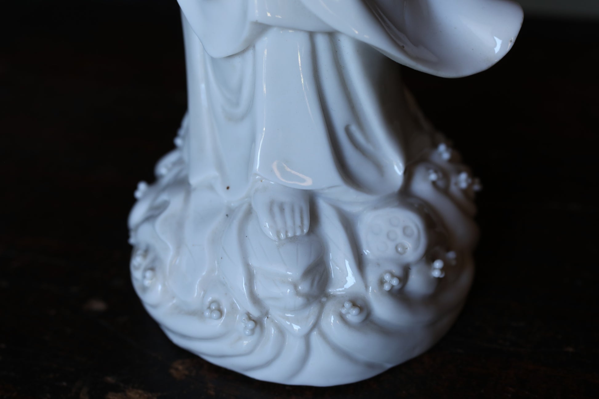 A close-up view of a white ceramic figurine, possibly a deity or religious figure, with intricate details and a textured surface.