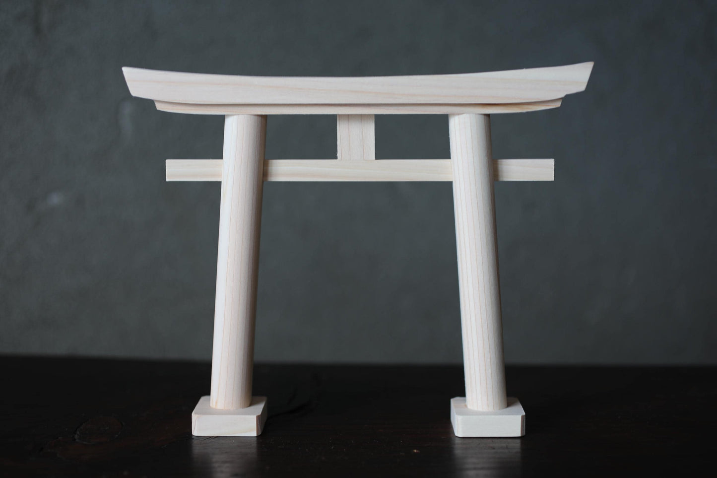 A wooden torii gate, a traditional Japanese gate, is shown against a dark background.