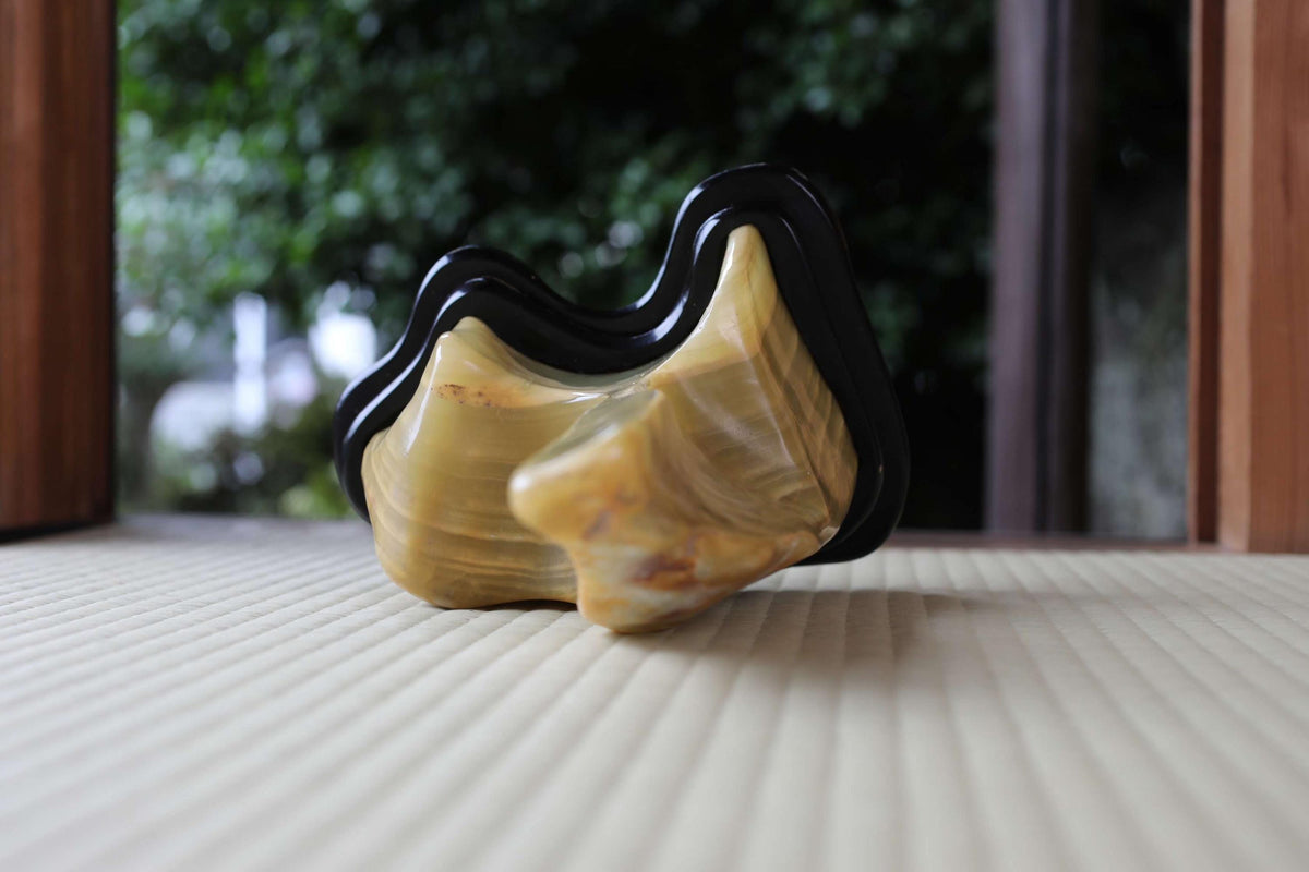 A close-up image of a yellow and black sculpture or figurine placed on a wooden surface.