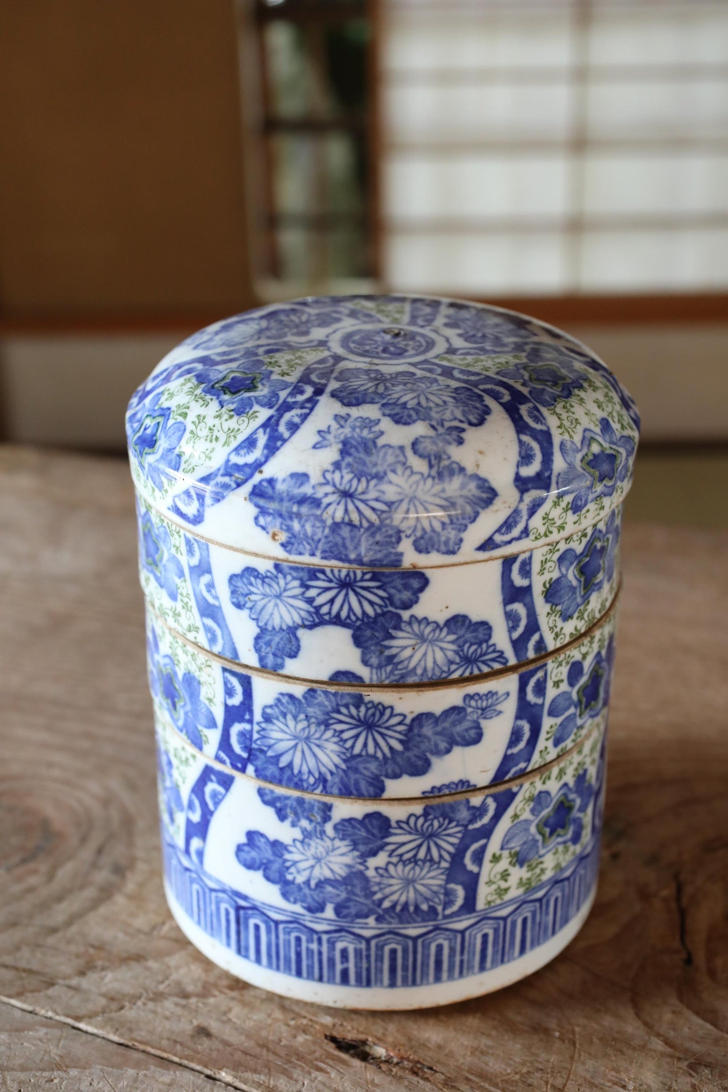 A decorative blue and white ceramic container with a floral pattern sits on a wooden surface.