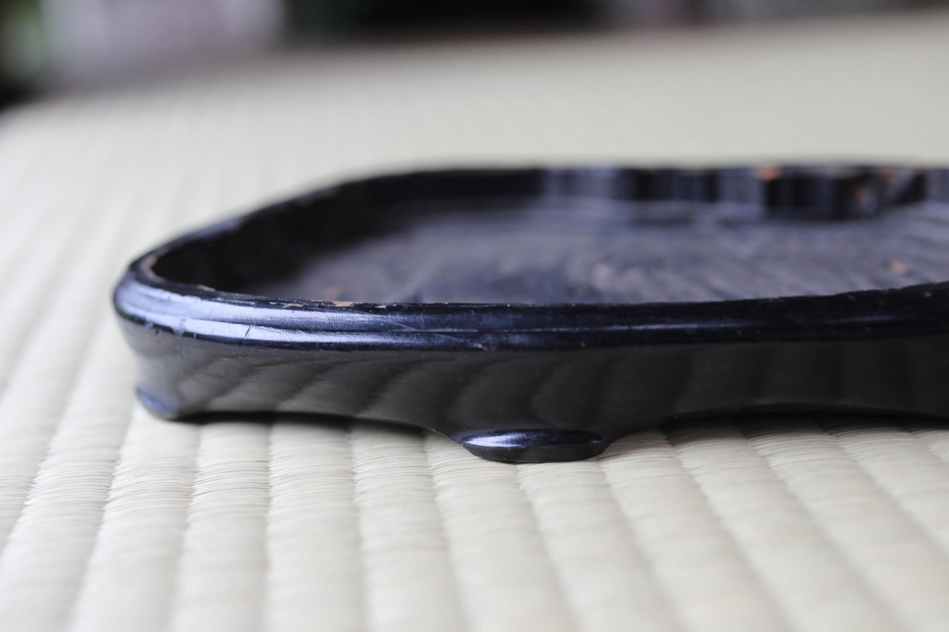 A black, rectangular tray with a glossy finish sits on a white, woven surface.