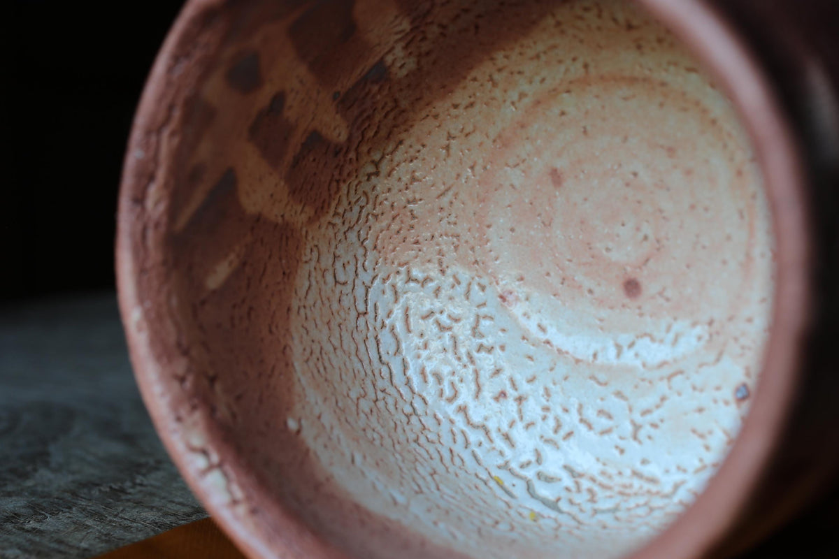 A close-up view of a ceramic bowl with a textured surface, featuring a circular pattern and a white interior.