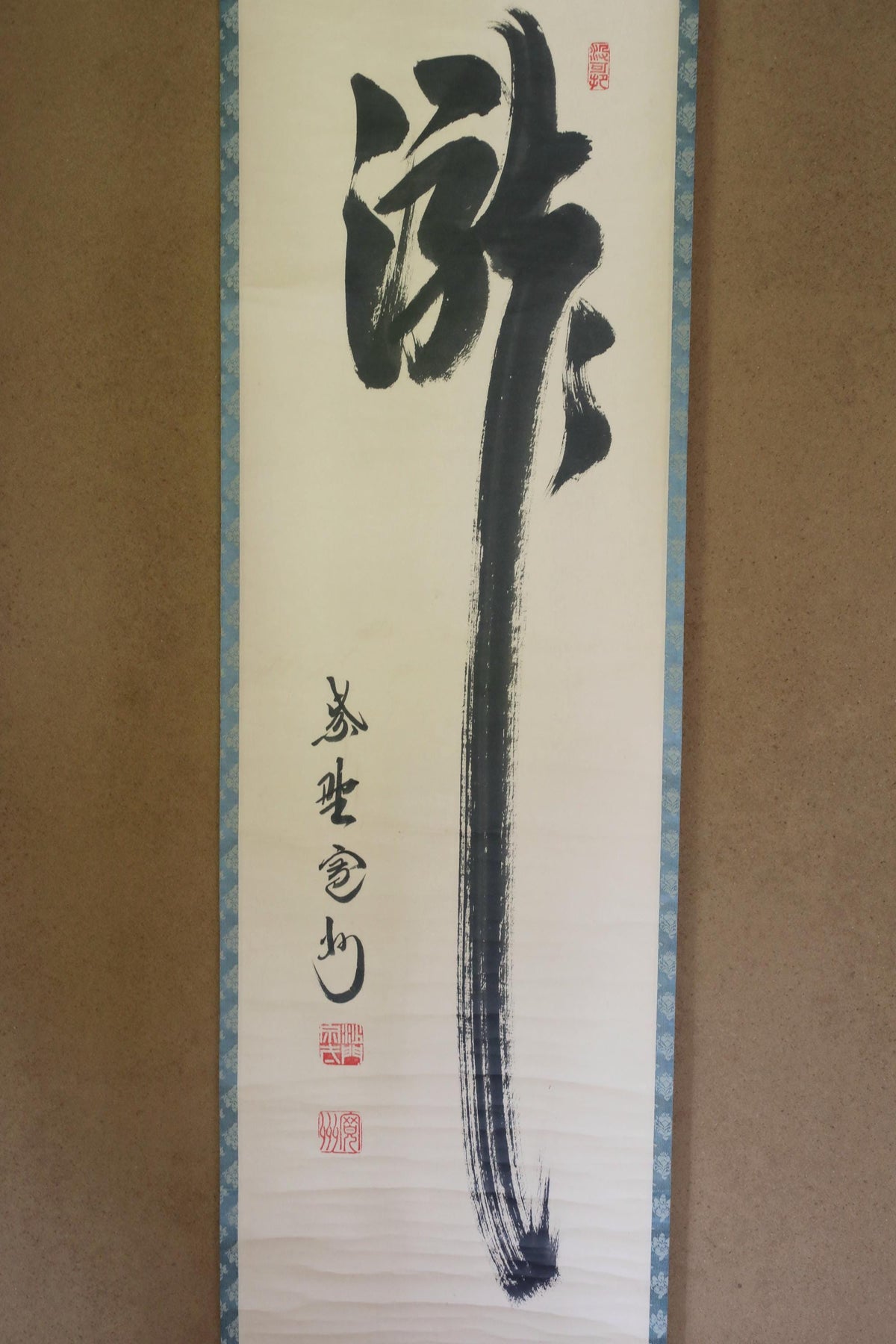 a large, black brush stroke on a white background, accompanied by Chinese characters.