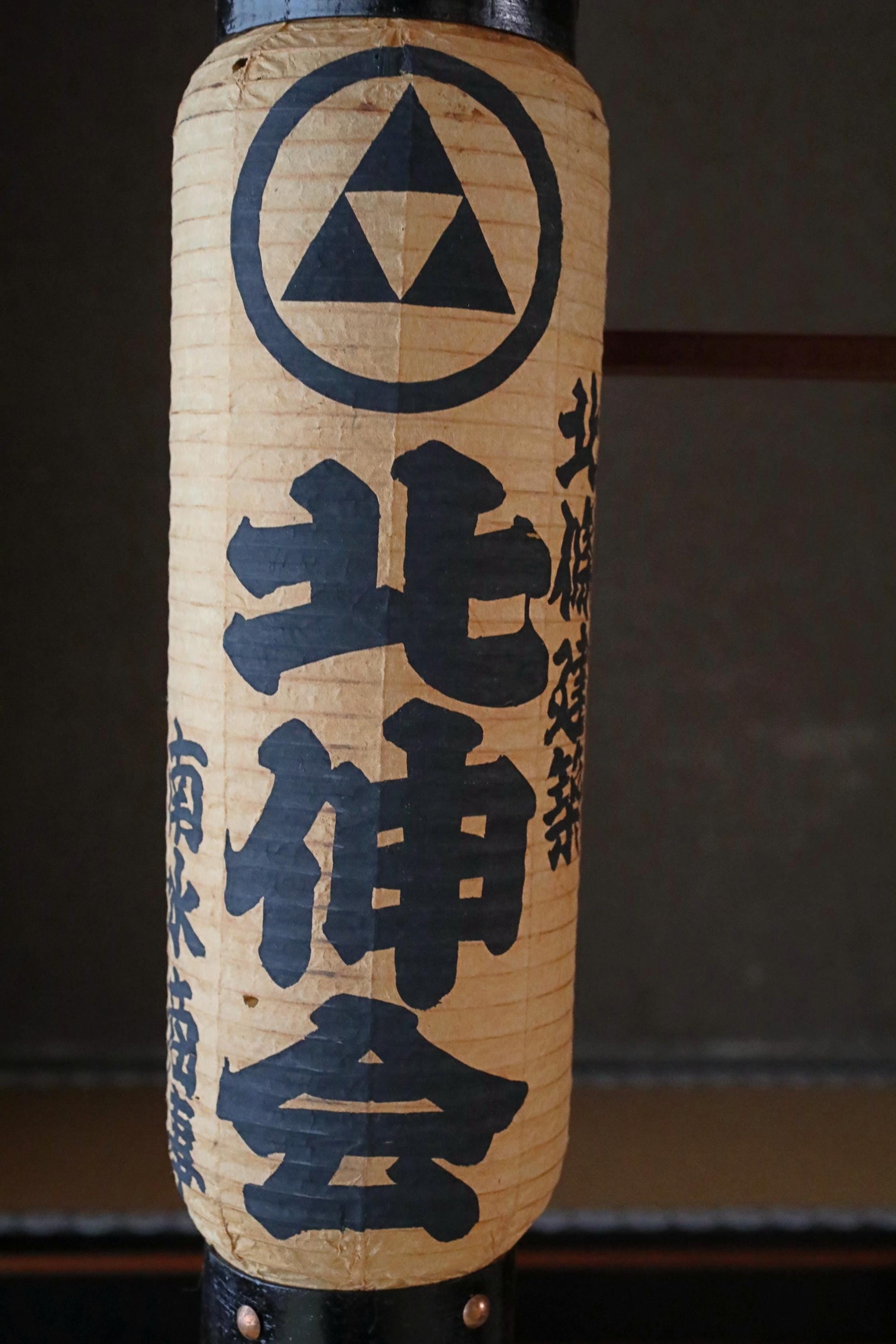 A paper lantern with Japanese text and a triangle symbol on it.
