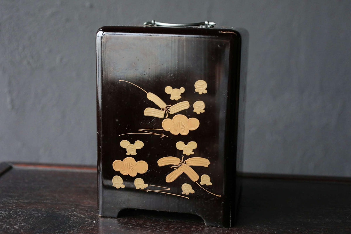 A black wooden box with a decorative design featuring gold butterflies and other small figures.
