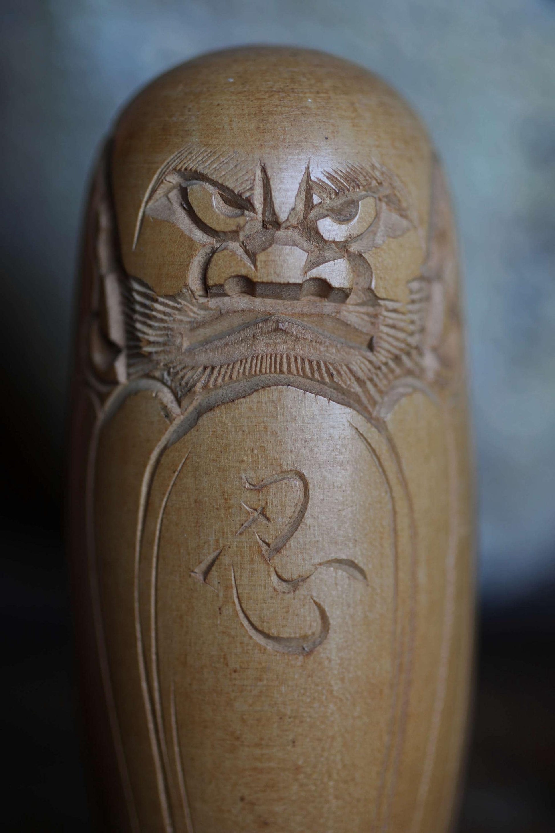 A close-up image of a wooden object, possibly a vase or sculpture, with intricate carved designs and patterns.
