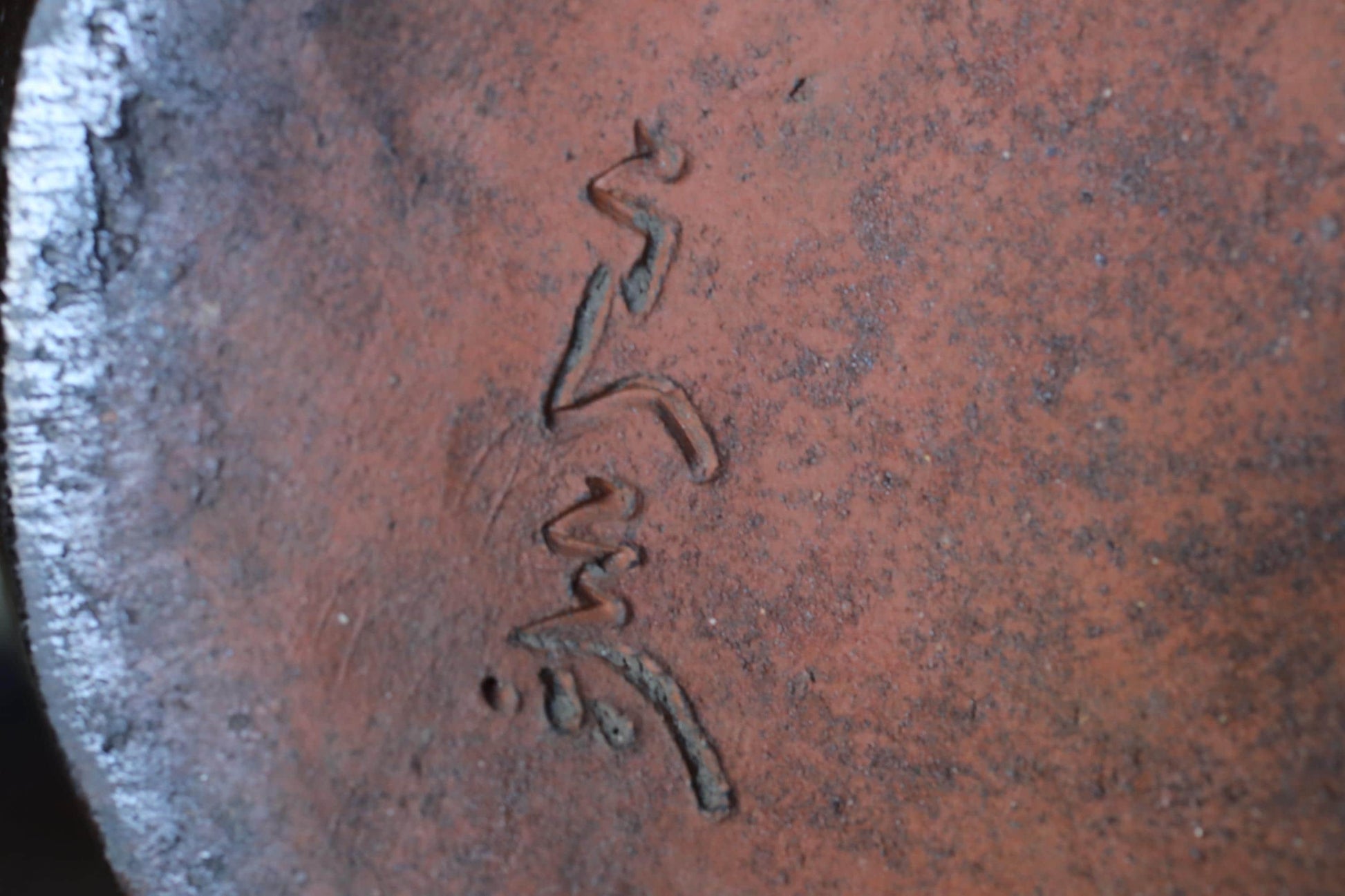 a close-up view of a reddish-brown surface with a carved design or text etched into it.