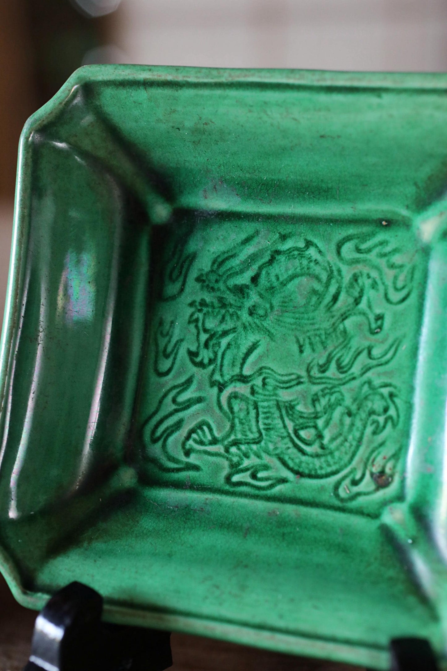 A green ceramic bowl with an intricate dragon design on it.