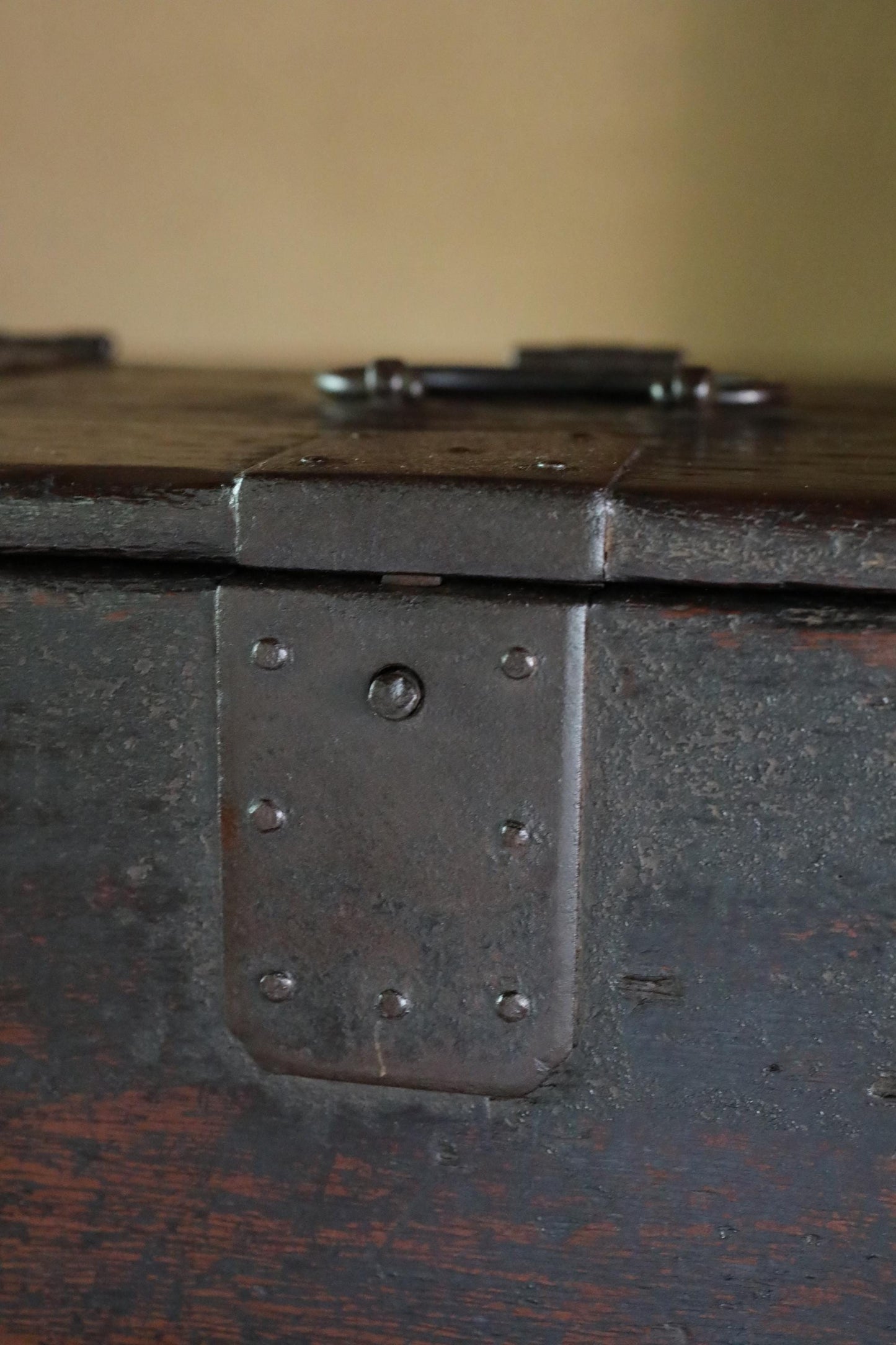 a close-up view of a metal latch on a wooden box, with a dark brown, weathered appearance.