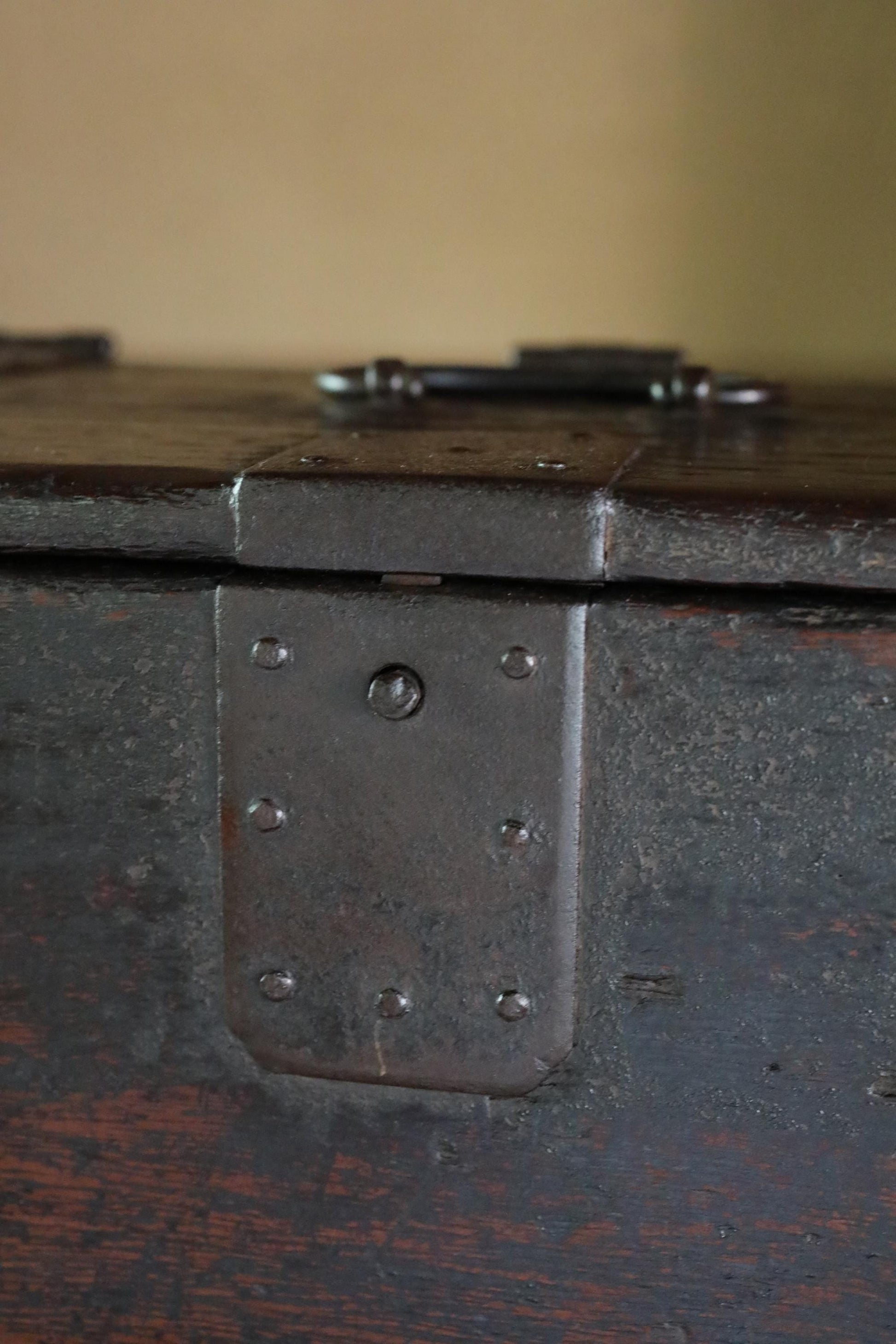 a close-up view of a metal latch on a wooden box, with a dark brown, weathered appearance.