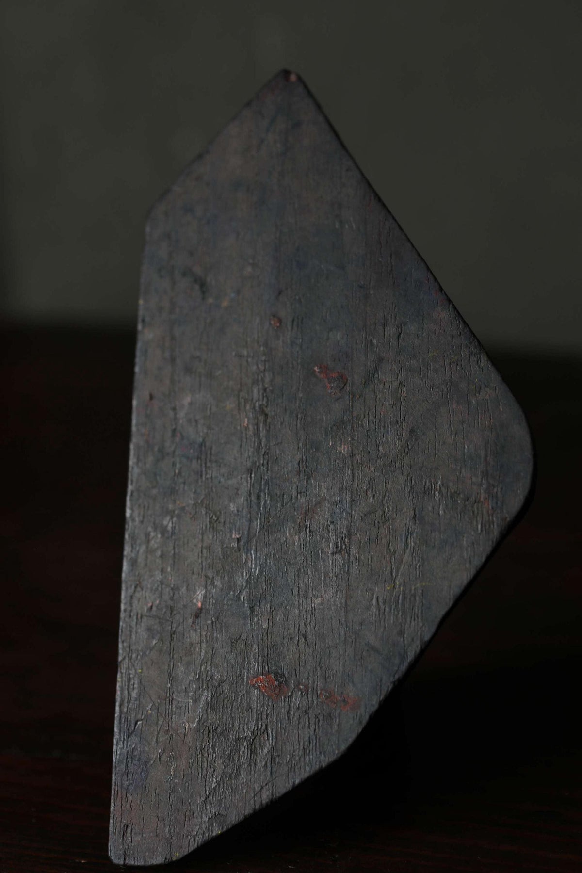 a close-up view of a dark, textured surface, possibly a piece of wood or metal, with a rough, uneven texture.