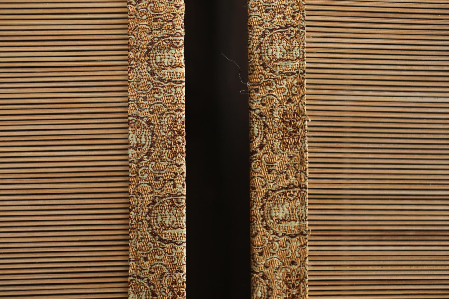 a close-up view of a patterned fabric, possibly a curtain or textile, with a dark background.