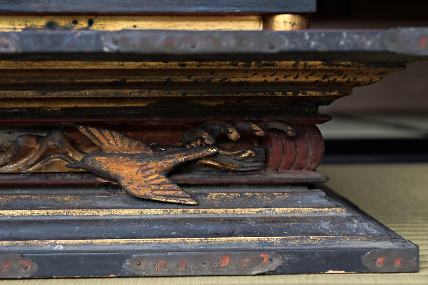 a close-up view of a decorative metal sculpture with a bird-like figure, resting on a dark surface.