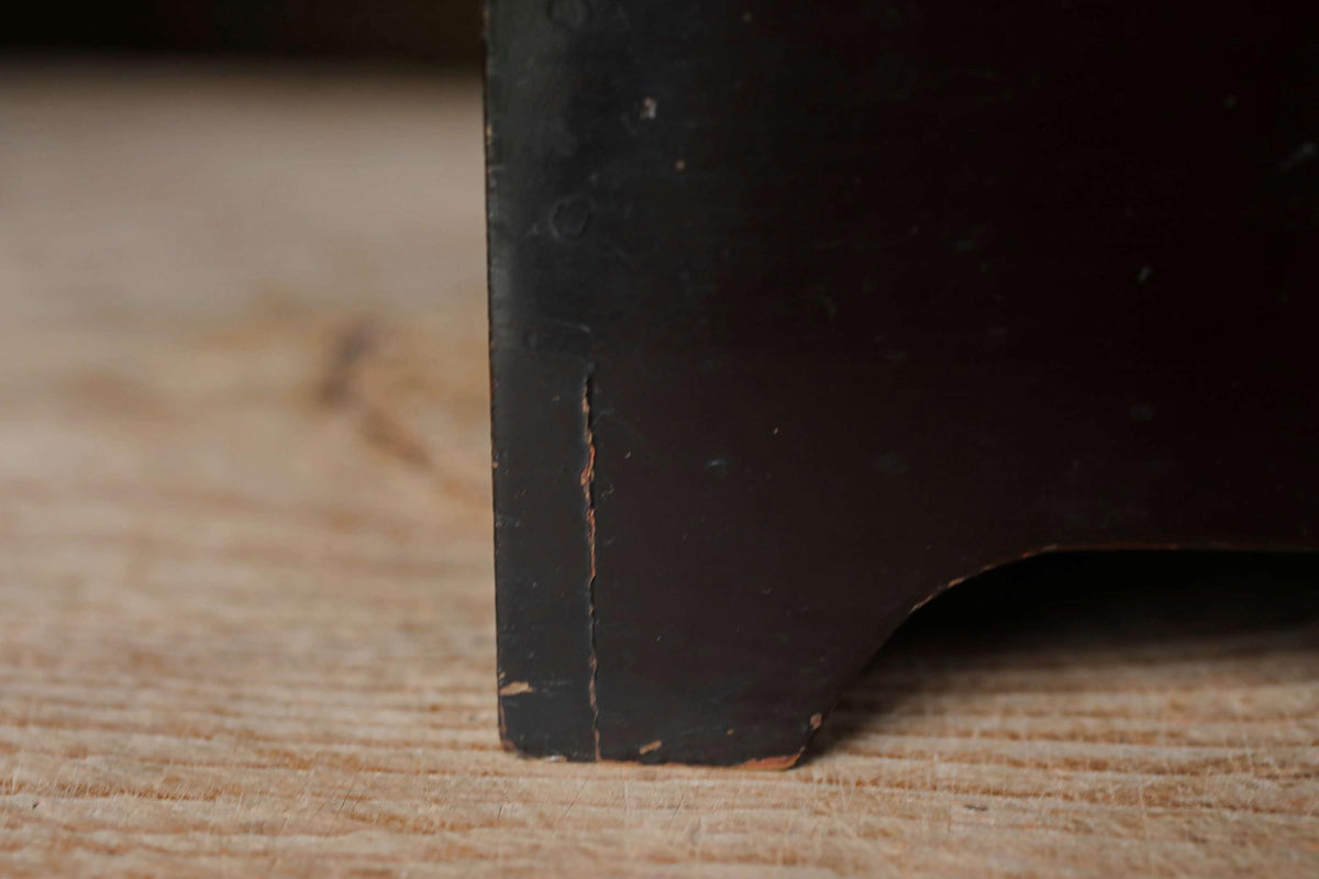 A close-up view of a dark wooden surface, with a visible crack or damage on the edge of the wood.