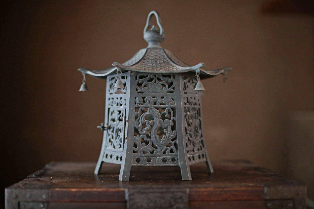 A decorative metal lantern with intricate designs and a pointed top sits on a wooden surface.