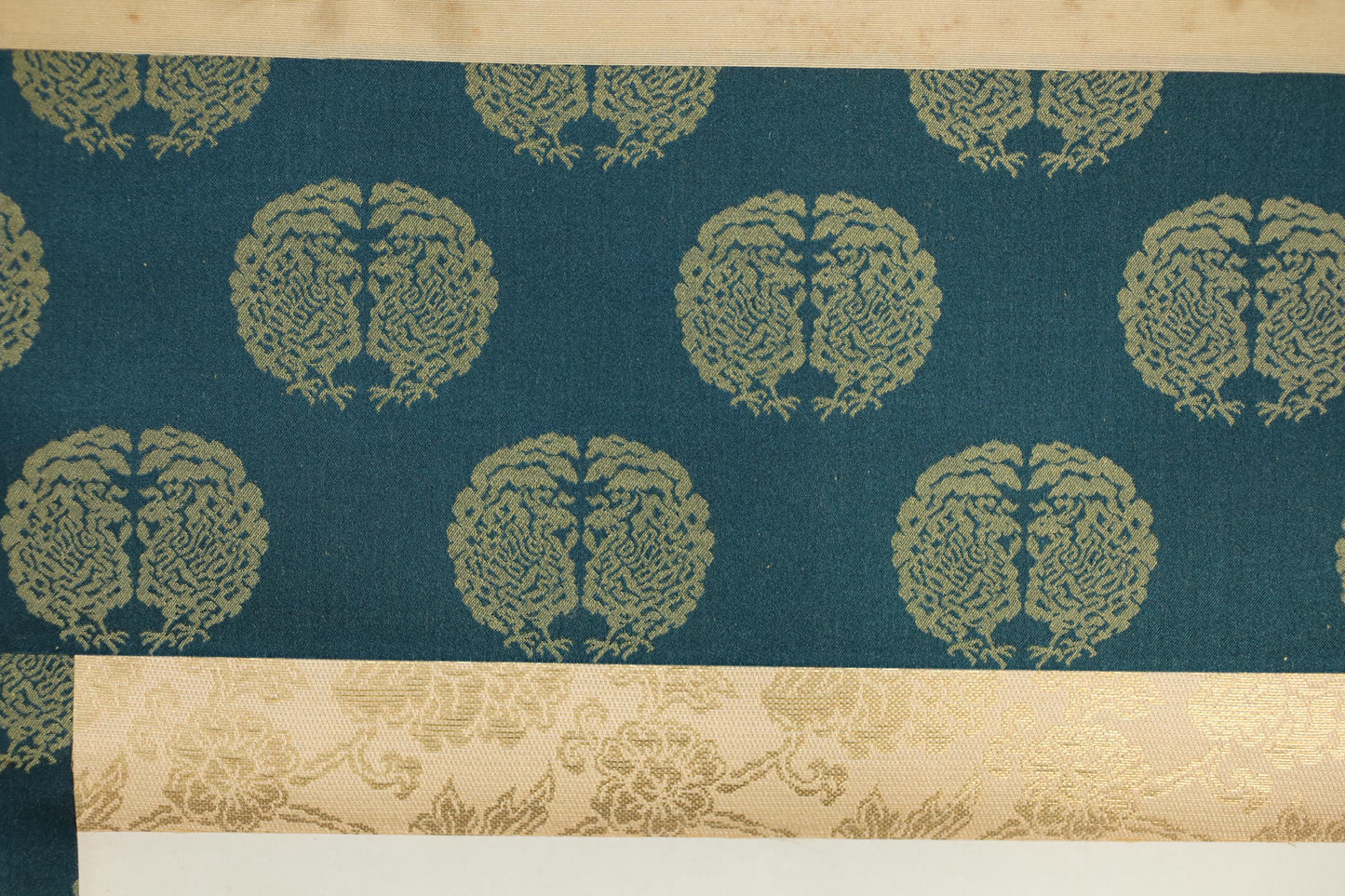 a close-up view of a patterned fabric with a repeating design of stylized tree-like shapes in shades of blue and gold.
