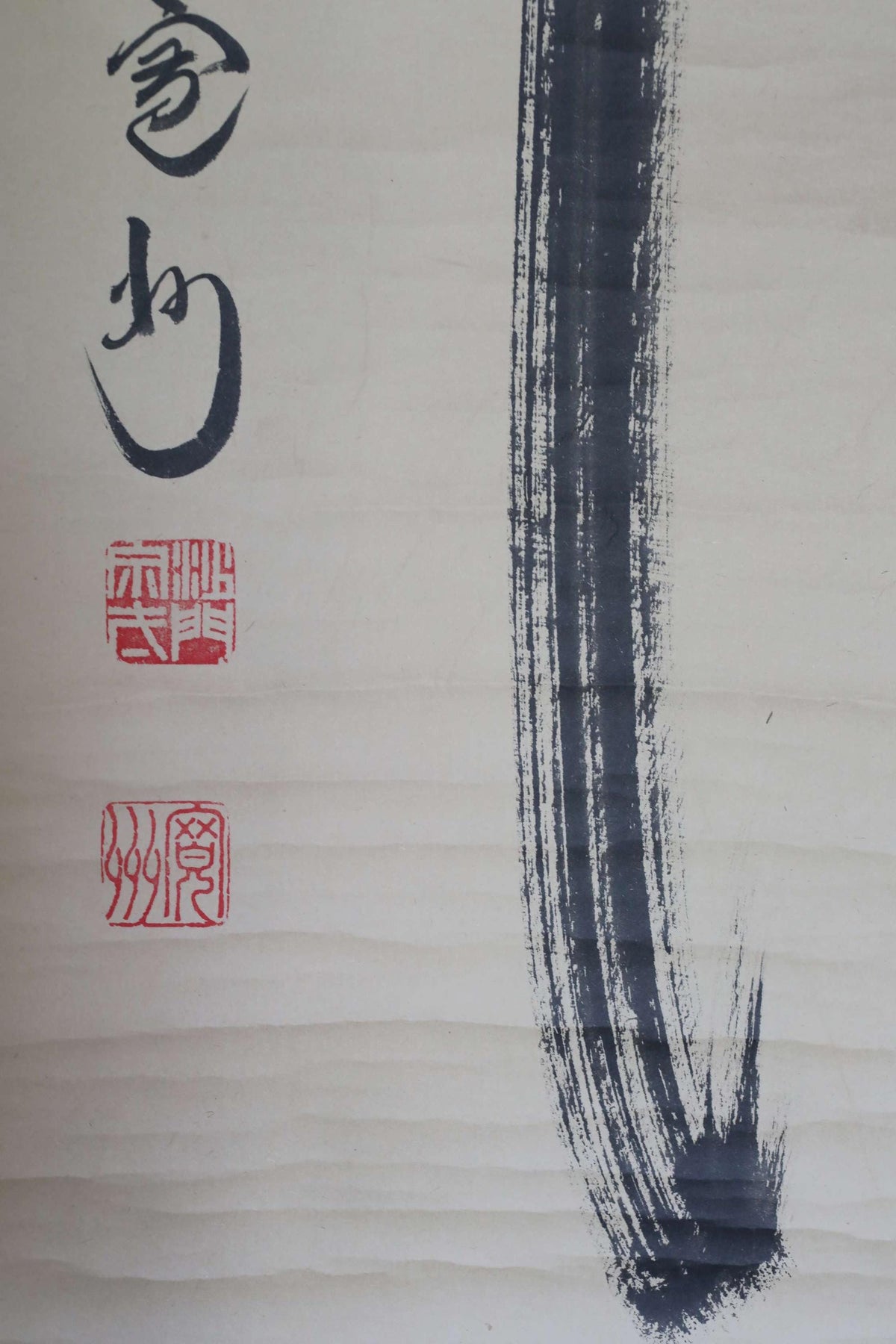 a close-up view of a black brush stroke on a white background, with some Chinese characters and a red stamp in the top left corner.