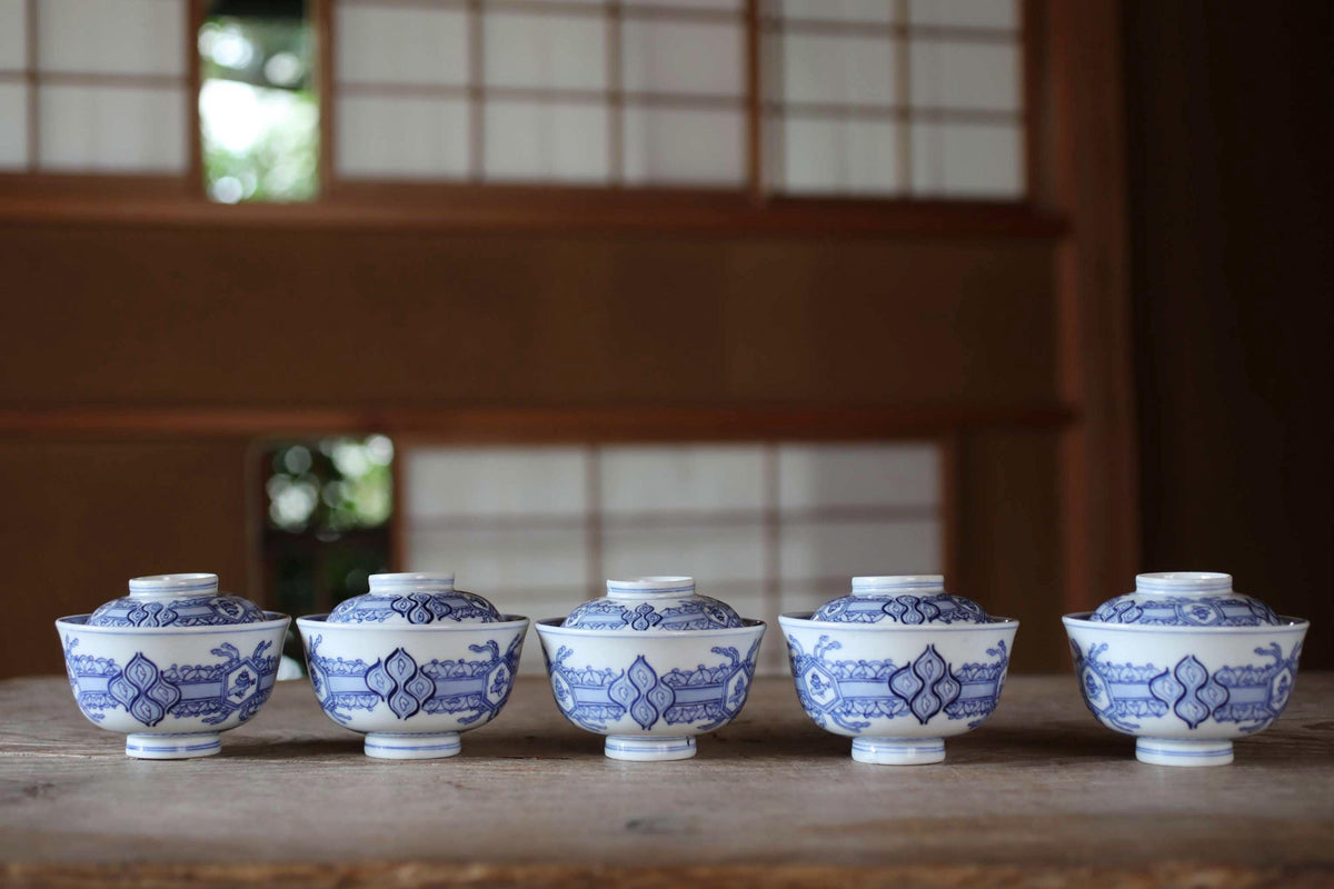 A row of blue and white porcelain bowls with intricate designs, arranged on a wooden surface.