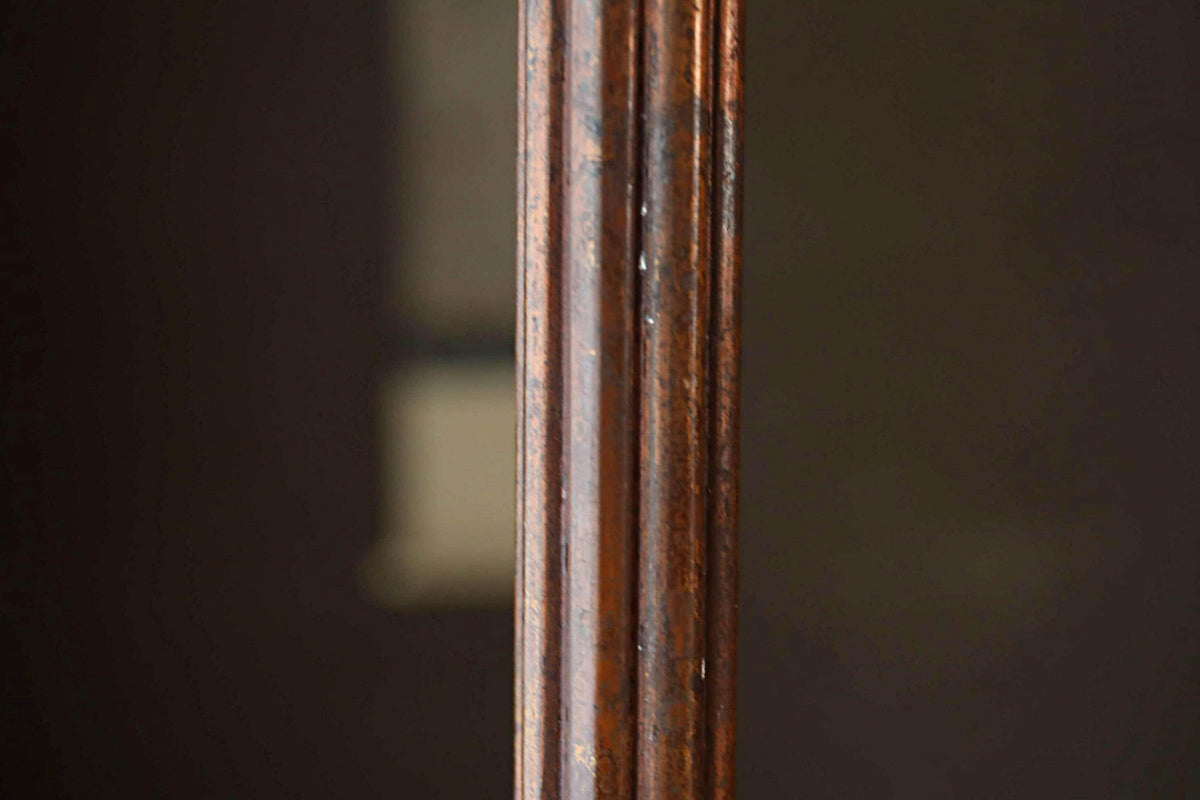 a close-up view of a wooden post or column, with a dark background that appears to be a window or door frame.