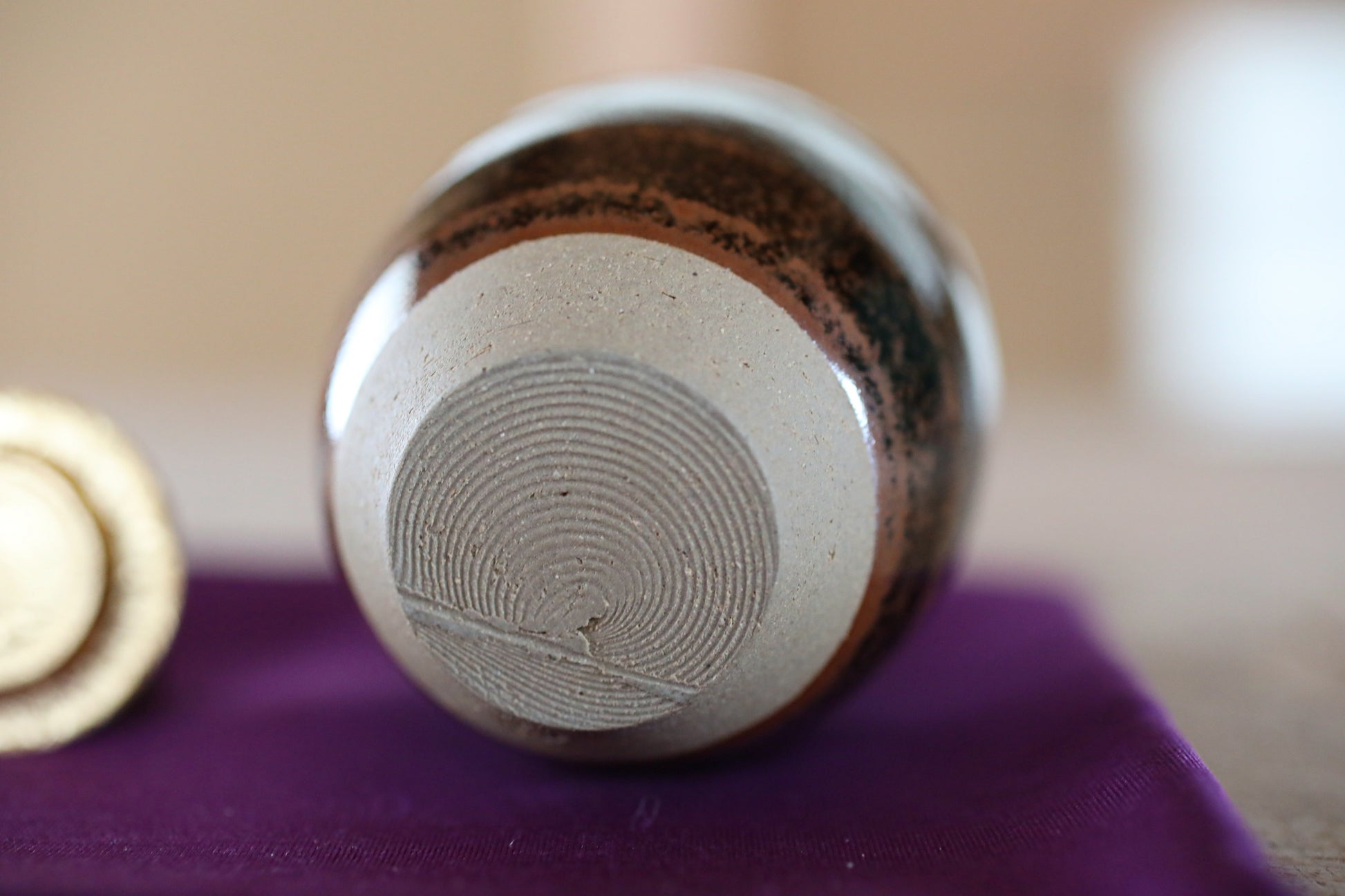 A close-up image of a ceramic object with a textured surface, resting on a purple cloth.
