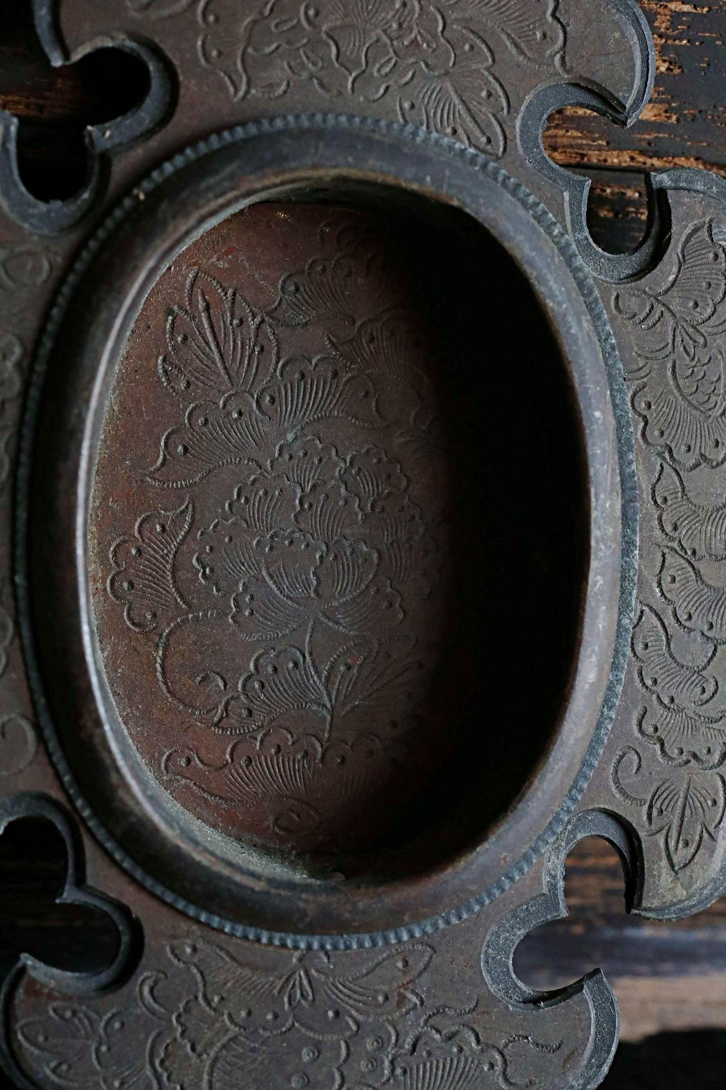 a close-up view of a decorative metal piece with an oval-shaped opening, showcasing intricate floral patterns.