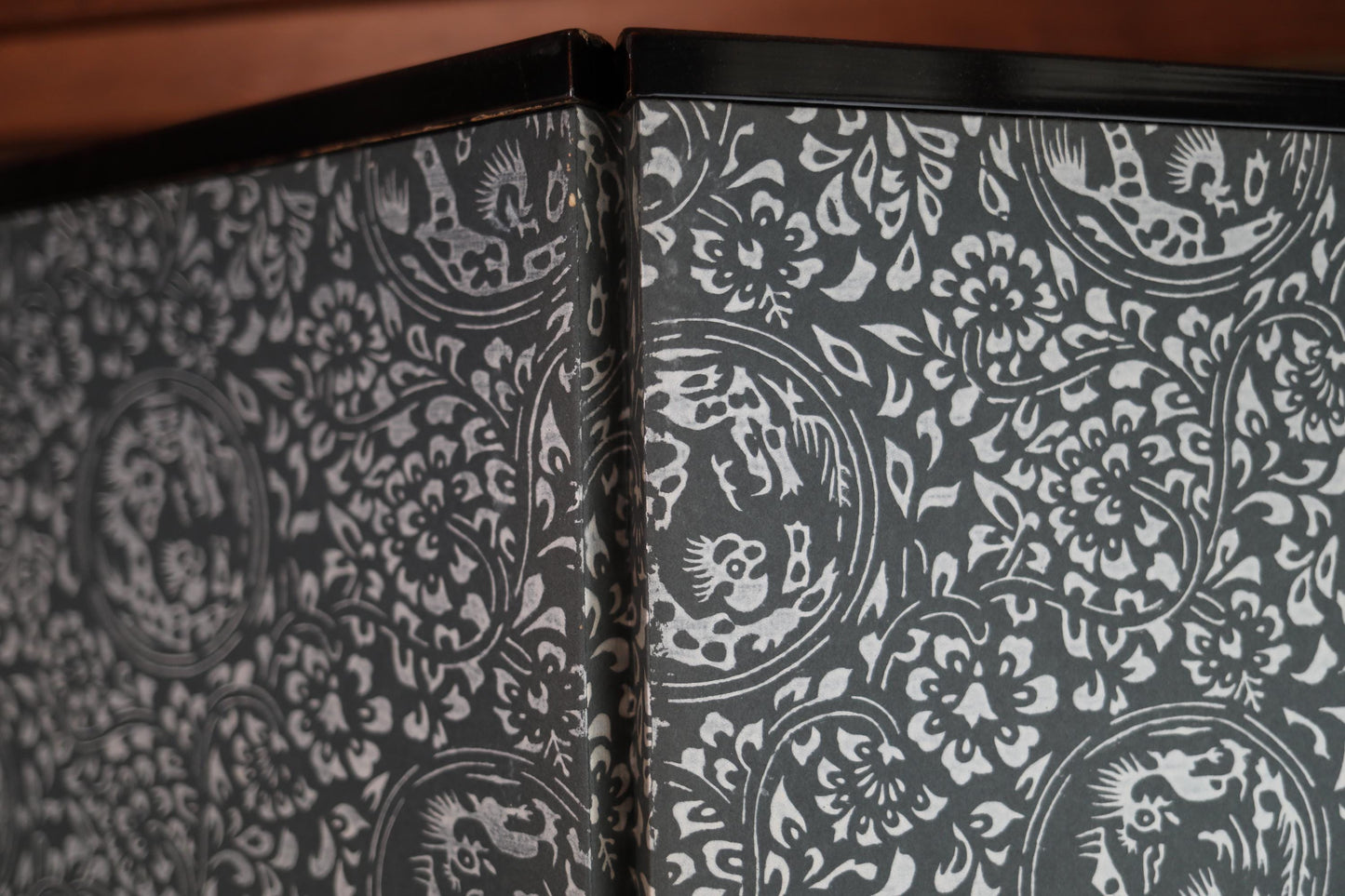 a close-up view of a decorative black and white patterned surface, possibly a wall or a piece of furniture. The pattern consists of intricate designs and floral motifs, creating a visually striking and detailed appearance.