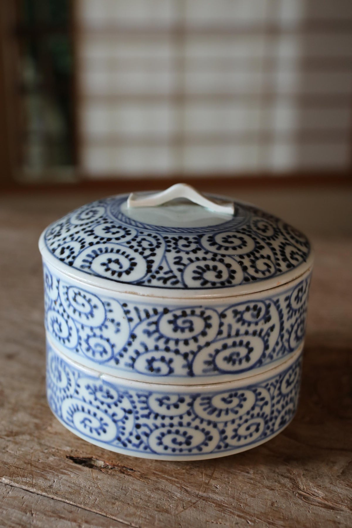 A decorative blue and white ceramic container with a lid, placed on a wooden surface.