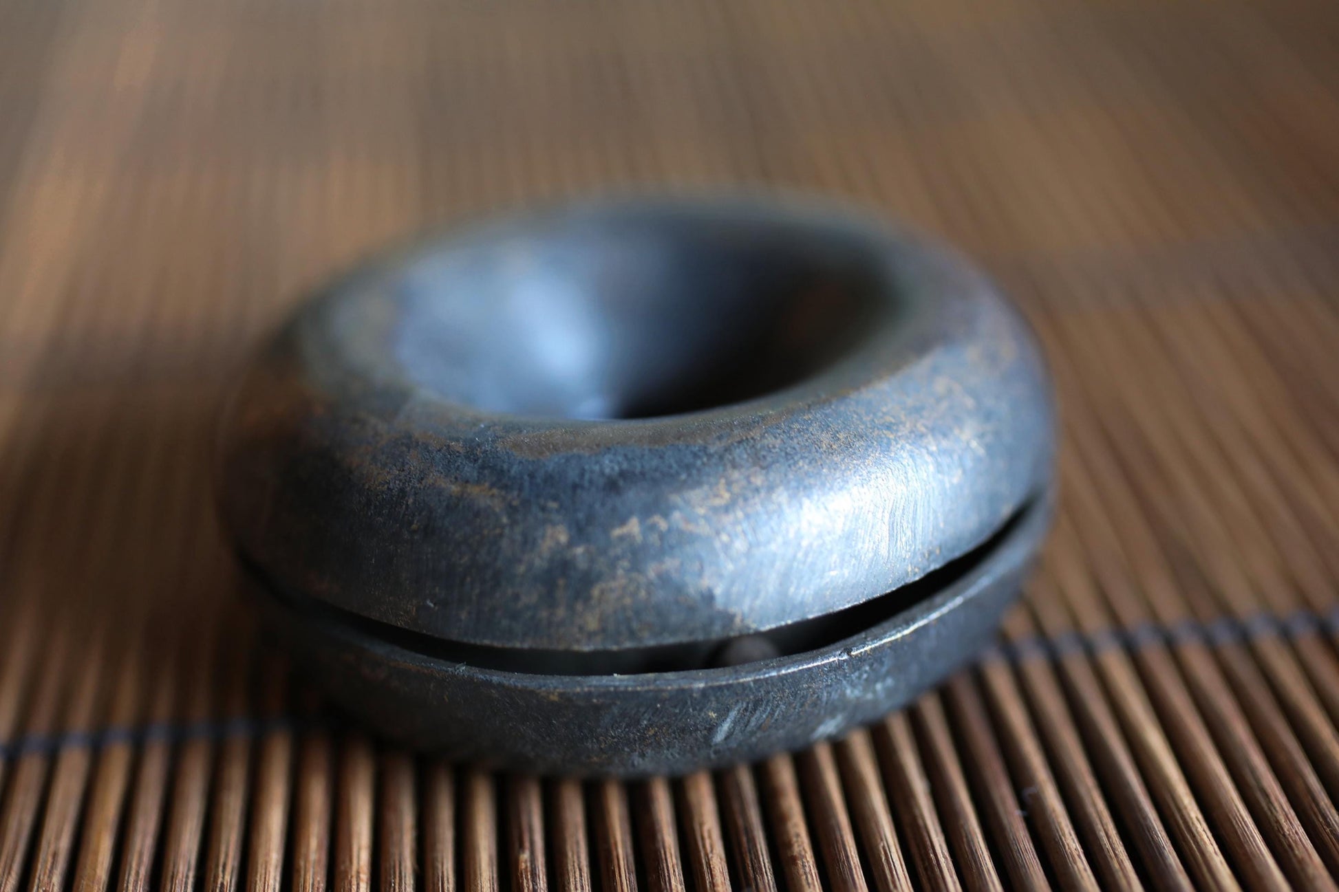 A close-up image of a metal object, possibly a small metal ring or container, resting on a wooden surface.