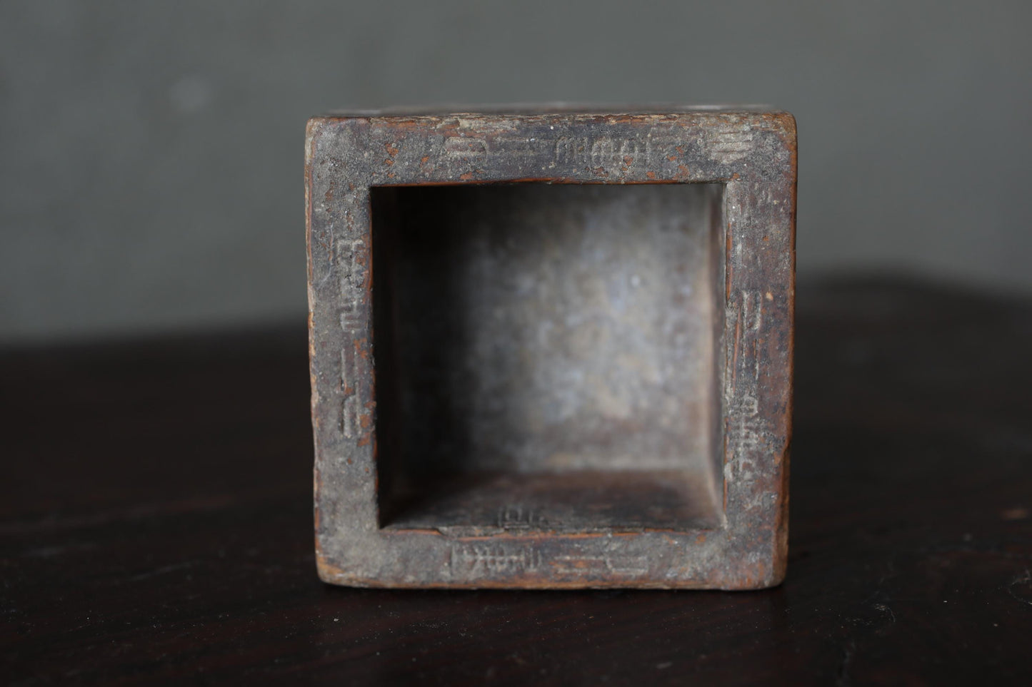 a small, square-shaped, metal object with a weathered, rust-colored surface.