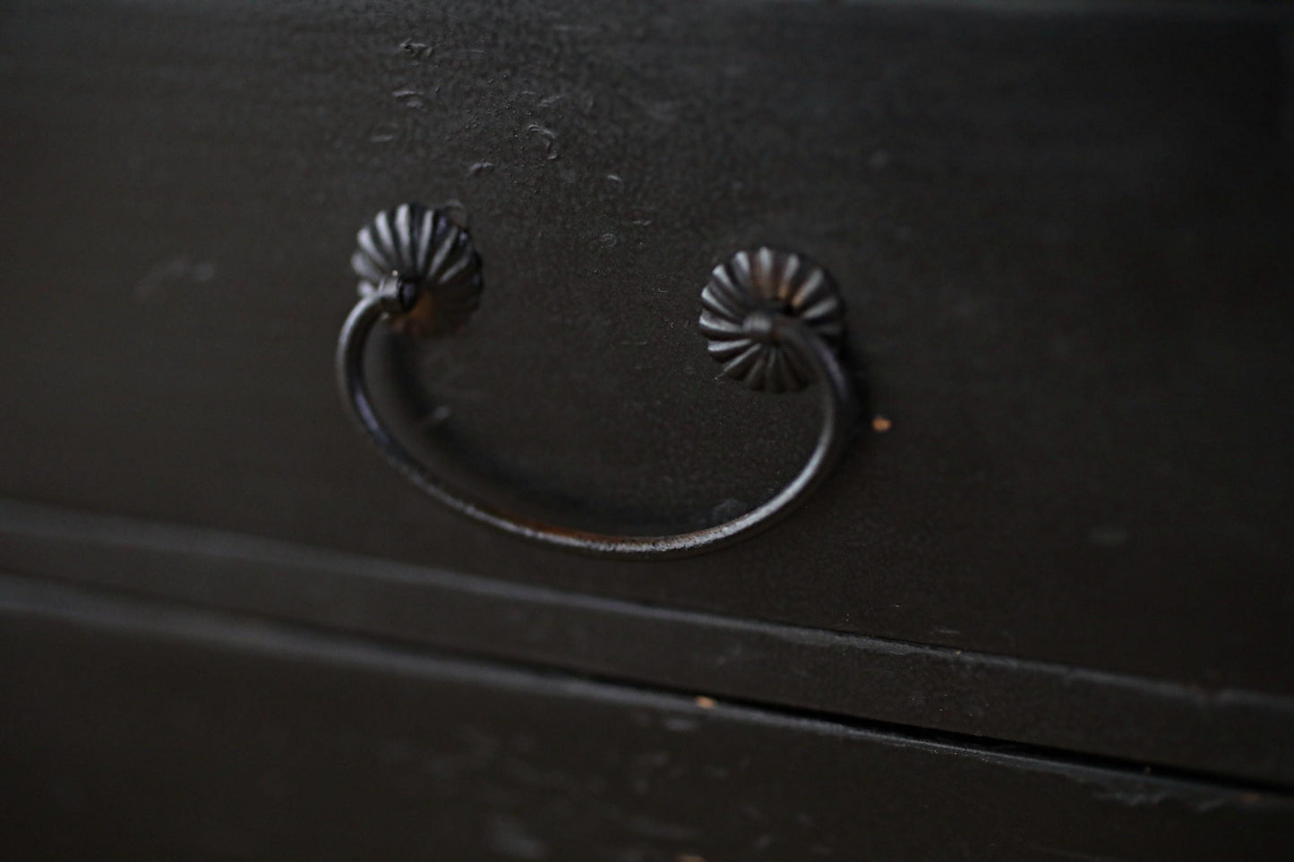 A close-up view of a black metal drawer handle with a curved design.