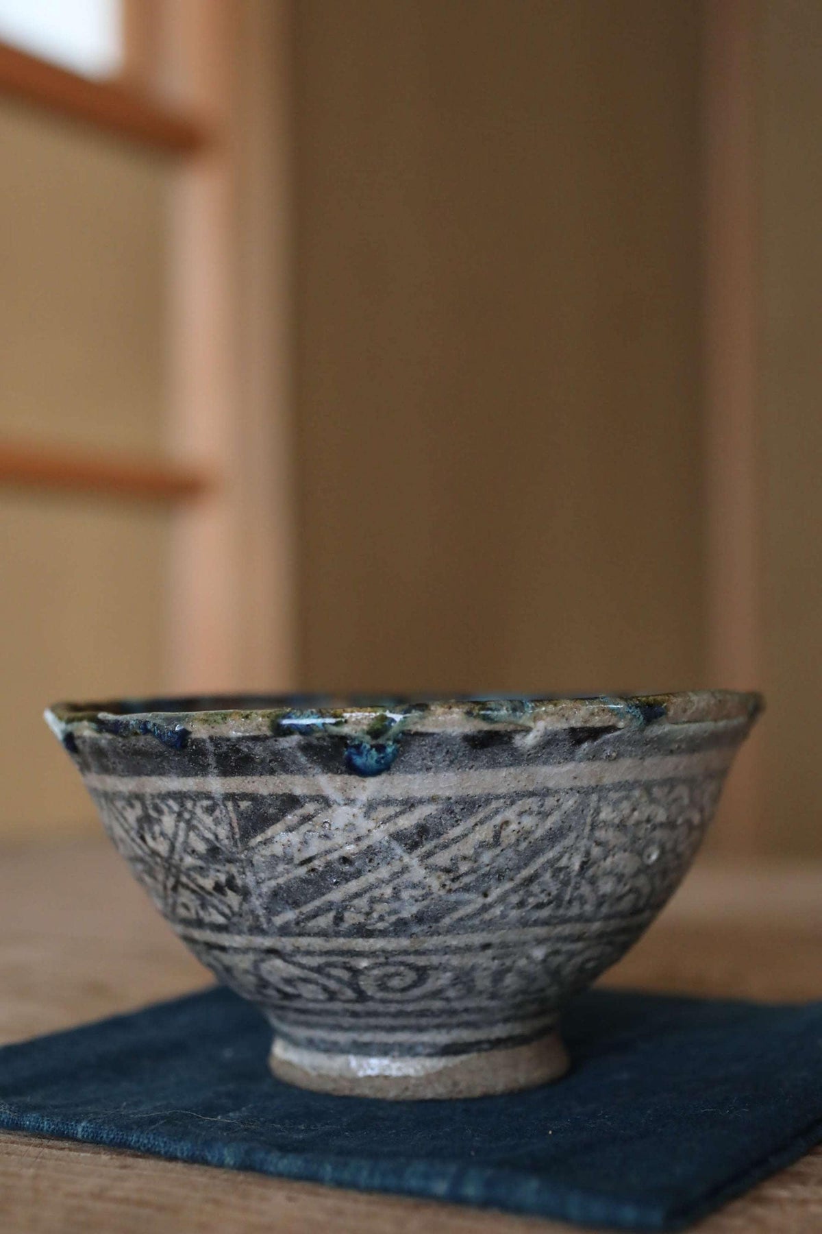 A ceramic bowl with intricate blue and white patterns sits on a blue cloth on a wooden surface.