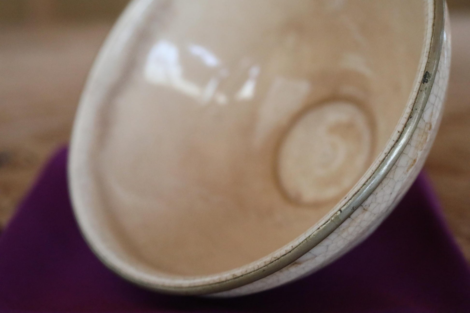 A close-up view of a white ceramic bowl with a silver rim, placed on a purple surface.