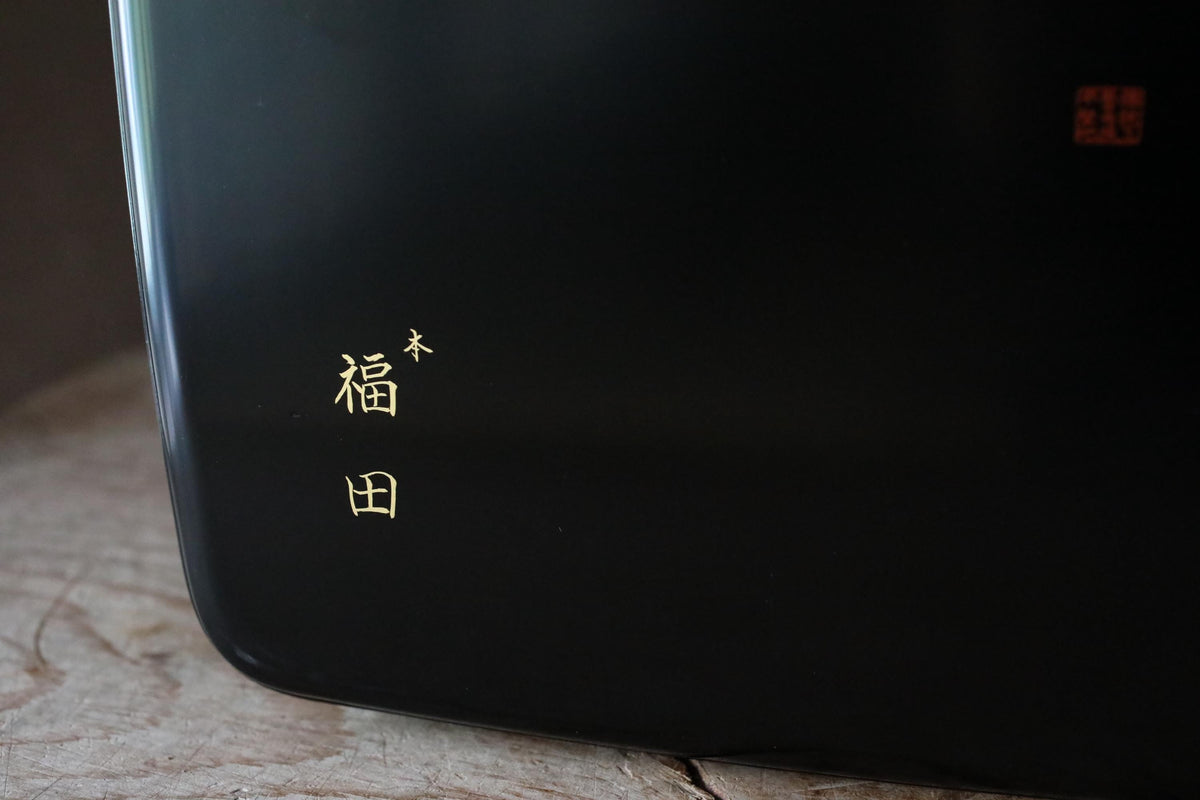 a close-up view of a black surface with a small gold symbol or text in the top left corner.