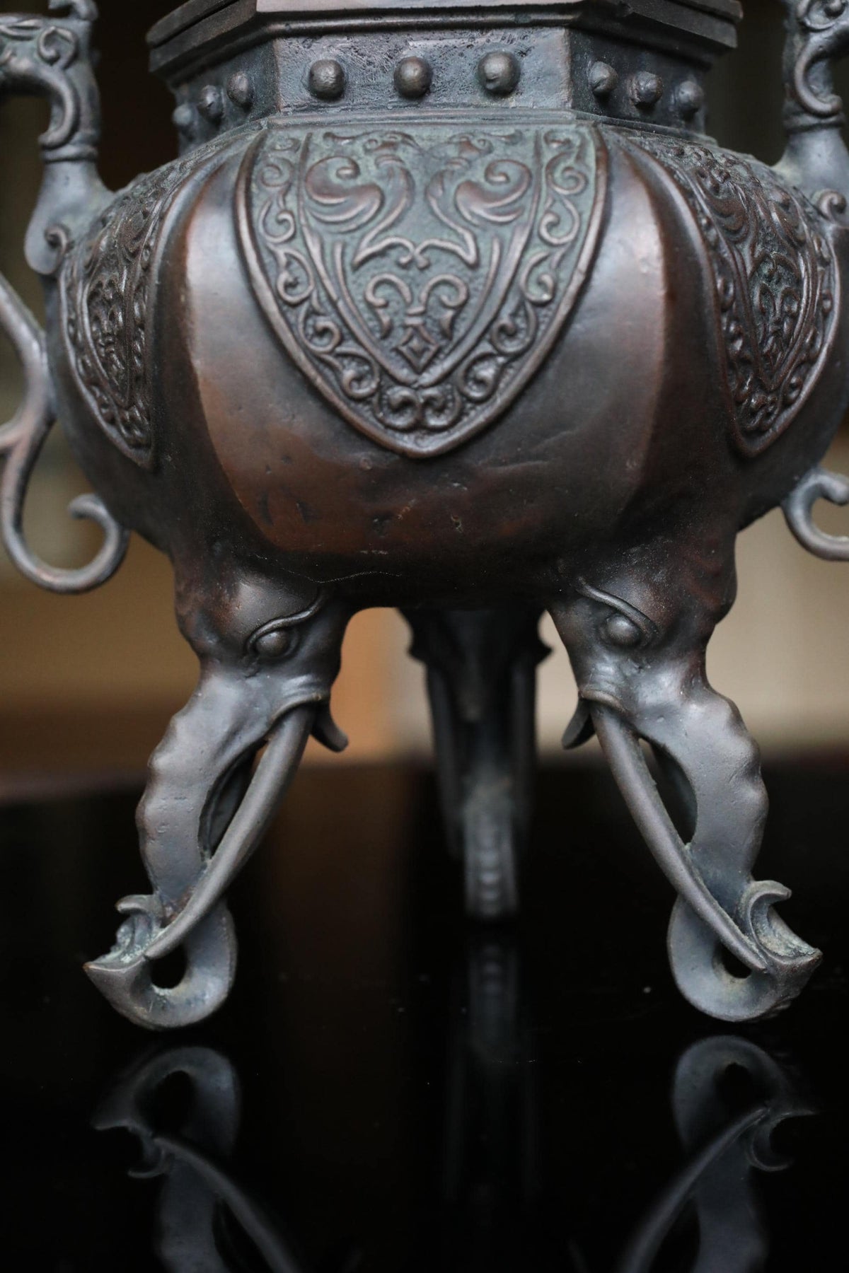 A close-up view of an ornate, antique-looking metal object, possibly a vase or urn, with intricate designs and patterns.