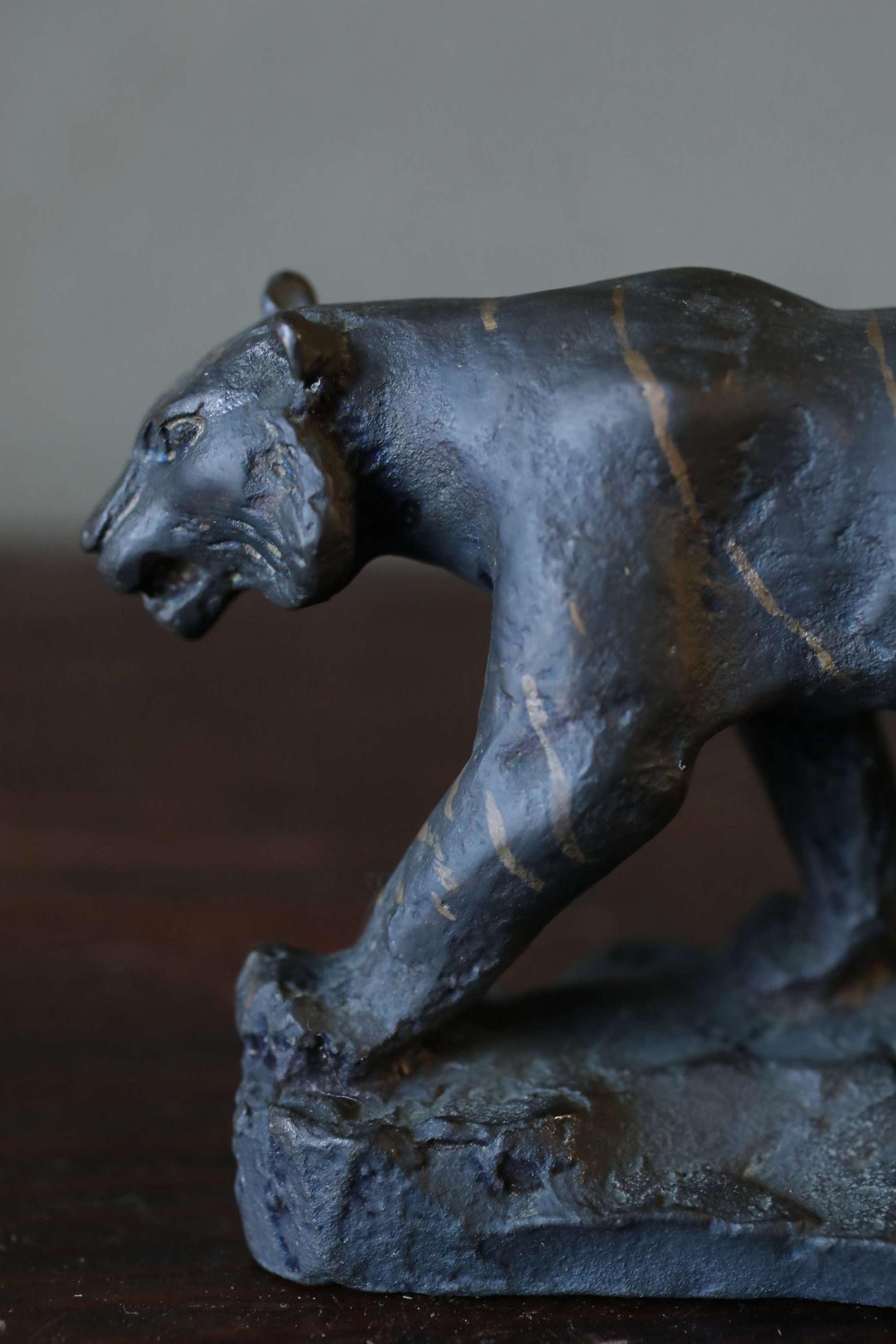 A bronze sculpture of a panther is shown in a close-up view, with a dark background.