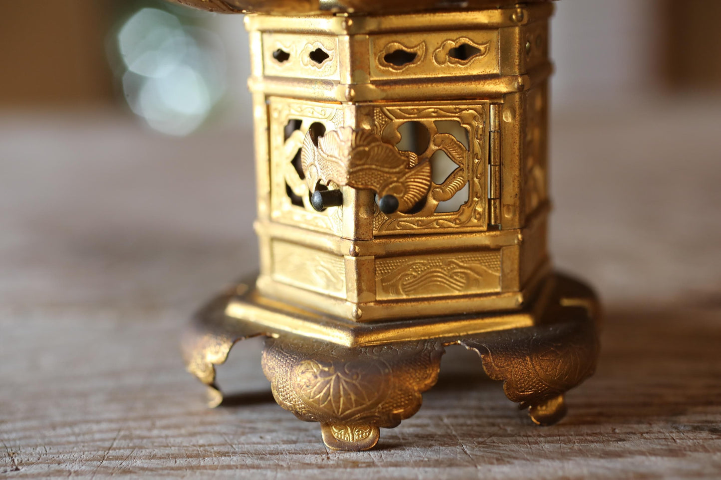A close-up view of a decorative golden object, possibly a piece of art or a traditional cultural item, placed on a wooden surface.